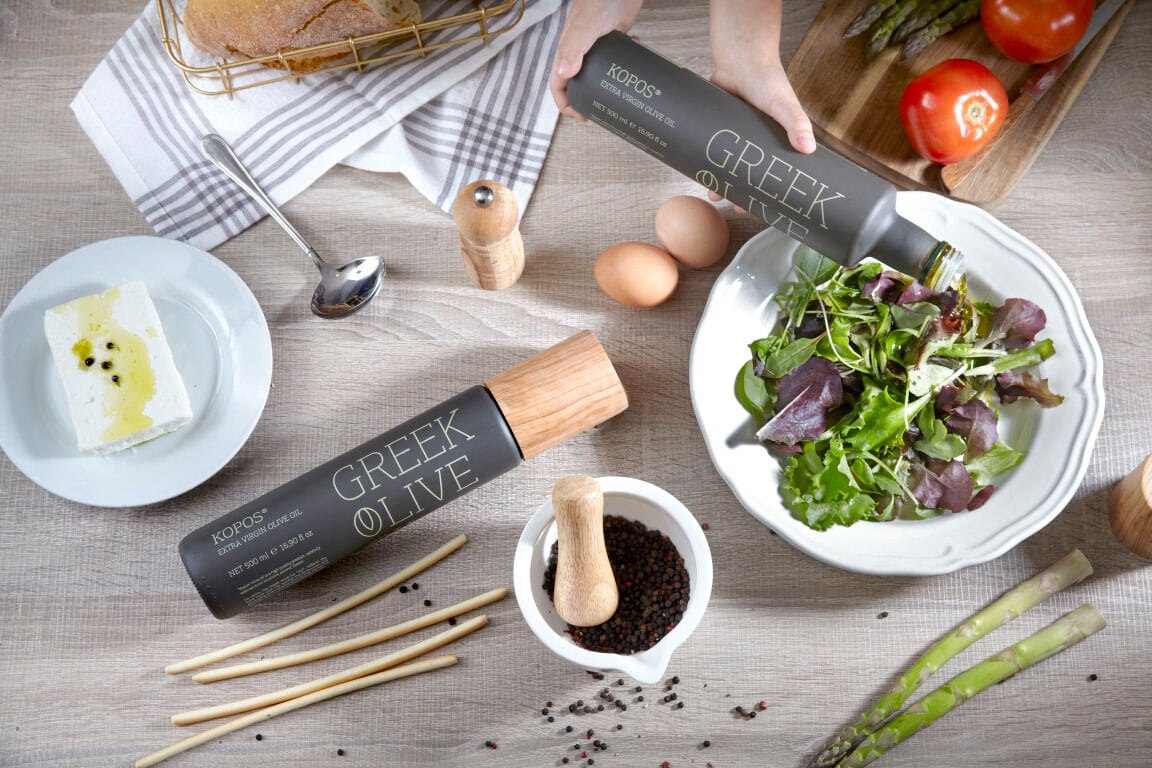 KOPOS® Greek Extra Virgin Olive Oil being drizzled over a fresh salad