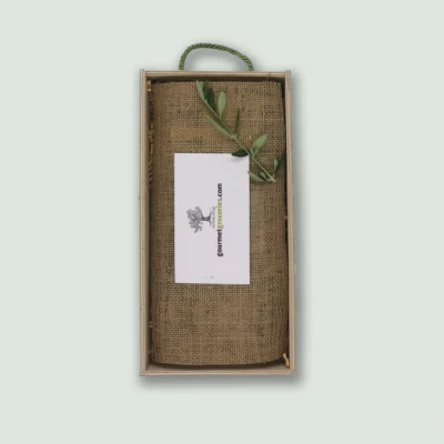 The inside of a Gourmet Groceries gift box, with products under a linen wrapping, a card, and an olive leaf.