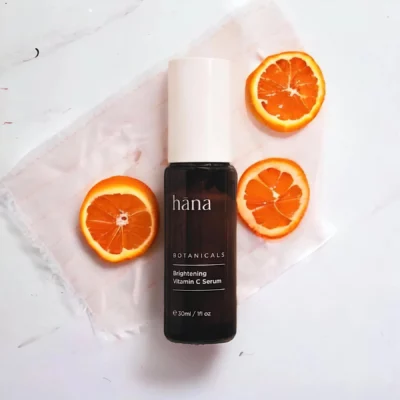 Close-up of Brightening Vitamin C Serum bottle next to oranges
