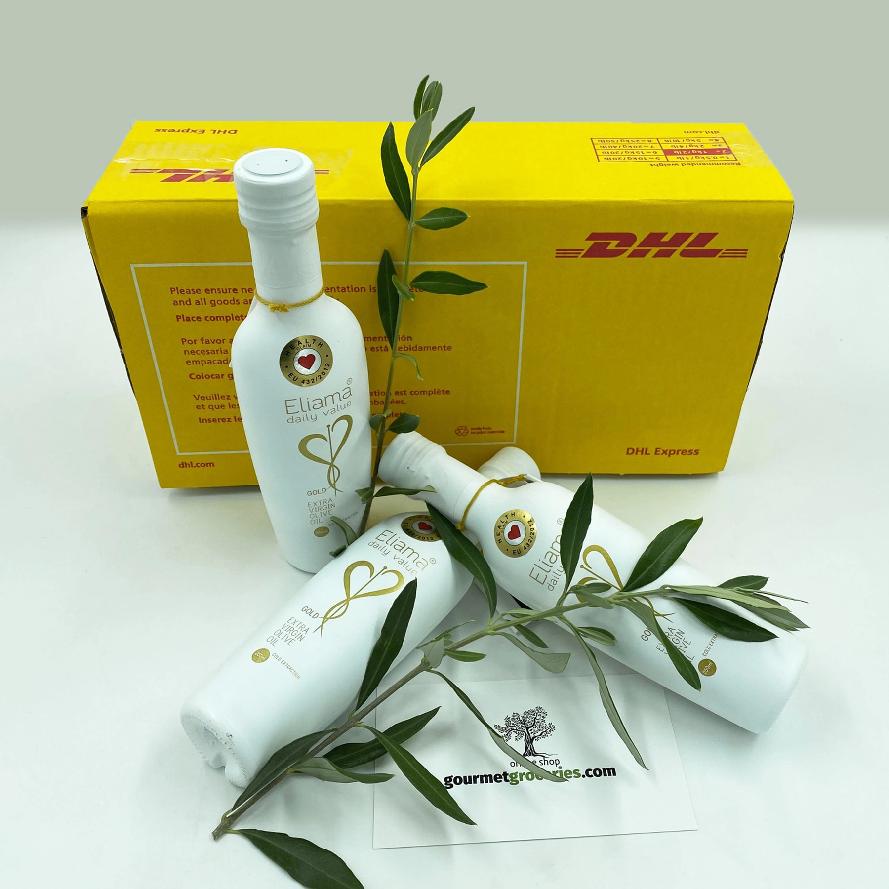Three 250ml bottles of Eliama Daily Value Extra Virgin Olive Oil Gold Bundle on a wooden kitchen table.