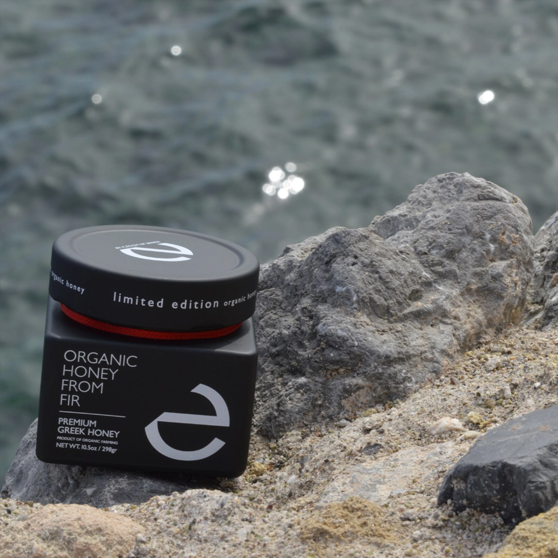 Eulogia’s Premium Honey bottle with the beach in the background,