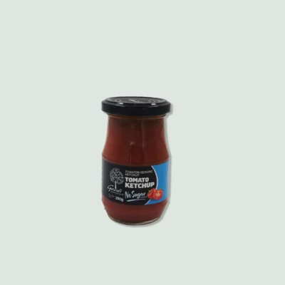 A jar of Geco Tomato Ketchup with no added sugar. The jar has a black lid and a blue and black label featuring a tomato illustration and text indicating the product name and ingredients.