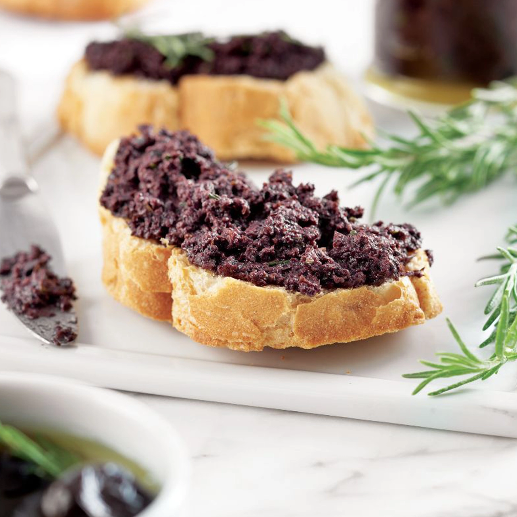 Marfuga Black Olive Spread spread on crispy bruschetta, perfect for Mediterranean appetizers.