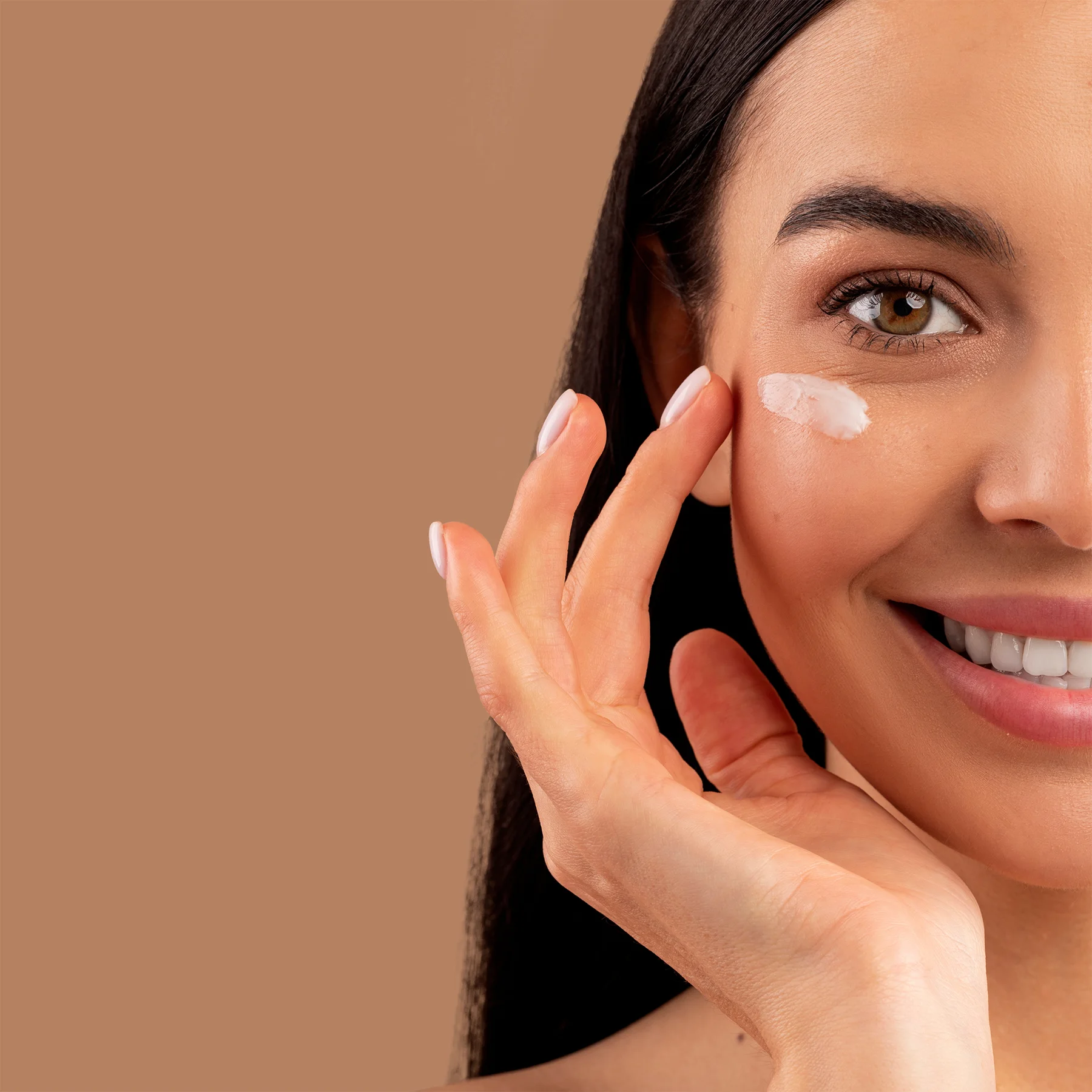 A woman gently applying OLIGAR Anti-Aging Serum to her face, demonstrating the serum's luxurious texture and ease of use in a daily skincare routine.