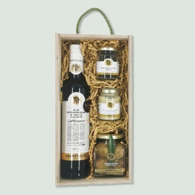 A gift box containing a bottle of extra virgin olive oil, a jar of whole summer truffles, a jar of artichoke hearts, and a jar of truffle sauce. The items are nestled in wood wool within a wooden box with a green rope handle.