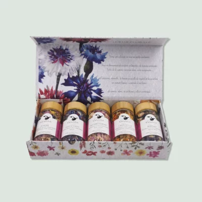 A box containing five jars of mixed herbs by Vanissa, labeled "Lueur Florale." The jars have golden lids and contain colorful blends of edible flowers and herbs. The box features a floral design with various flowers illustrated on it, and the interior lid has a poetic French text and floral imagery.