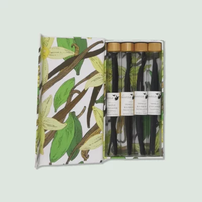A box containing four vanilla pods in glass tubes by Vanissa. The box has a botanical design with vanilla flowers and pods. The vanilla pods are of two varieties: Bourbon Madagascar and D'Ouganda Planifolia.